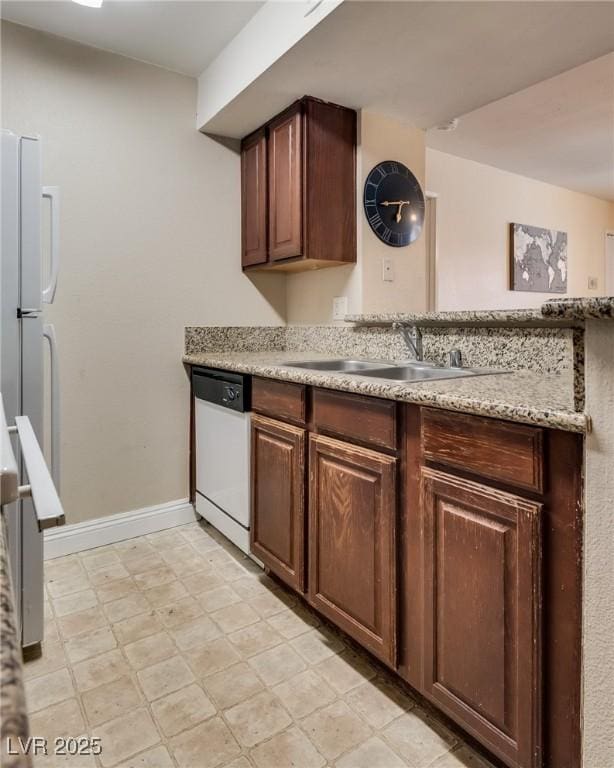 kitchen featuring white appliances, baseboards, light floors, and a sink