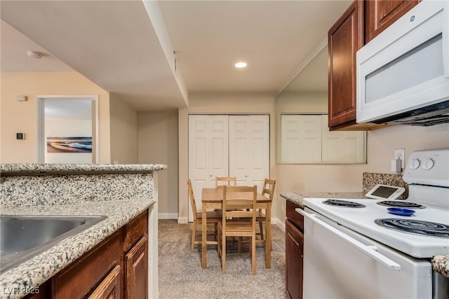 kitchen featuring light stone counters, recessed lighting, light colored carpet, white appliances, and baseboards