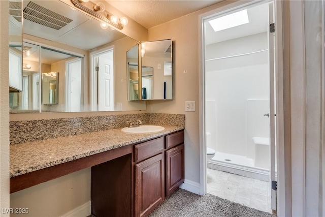 bathroom with visible vents, toilet, a stall shower, vanity, and baseboards