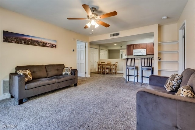 living room featuring ceiling fan, carpet floors, visible vents, and baseboards