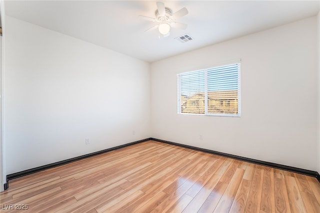 spare room featuring light wood-style floors, visible vents, baseboards, and a ceiling fan