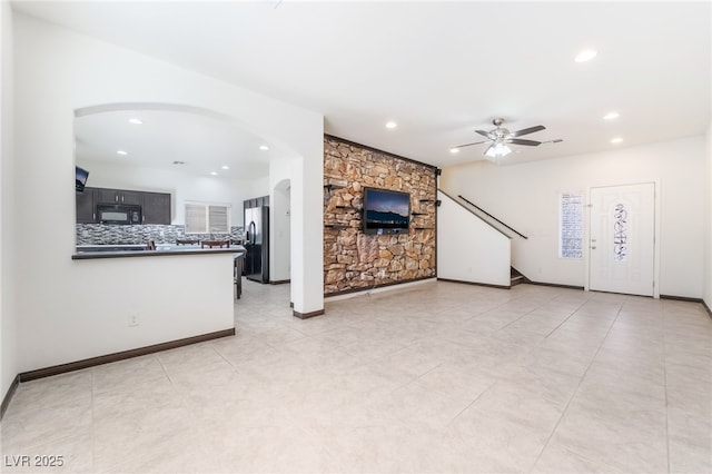 unfurnished living room featuring arched walkways, ceiling fan, baseboards, and recessed lighting