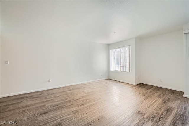 empty room featuring wood finished floors and baseboards