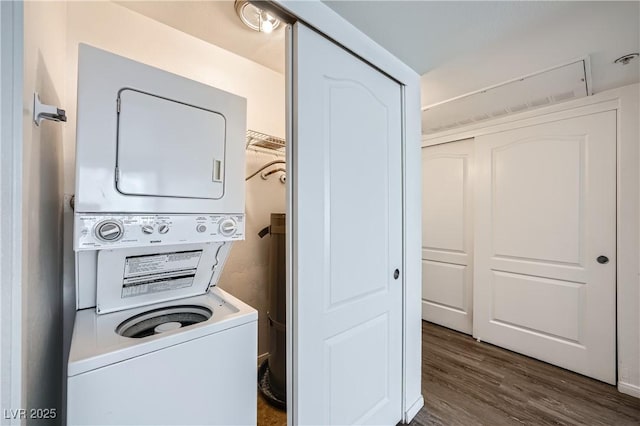 clothes washing area featuring stacked washer and dryer, laundry area, and dark wood finished floors