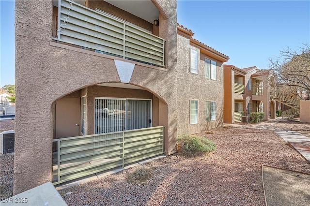 view of side of home featuring a tiled roof and stucco siding