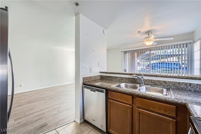 kitchen featuring light tile patterned floors, brown cabinetry, ceiling fan, stainless steel appliances, and a sink