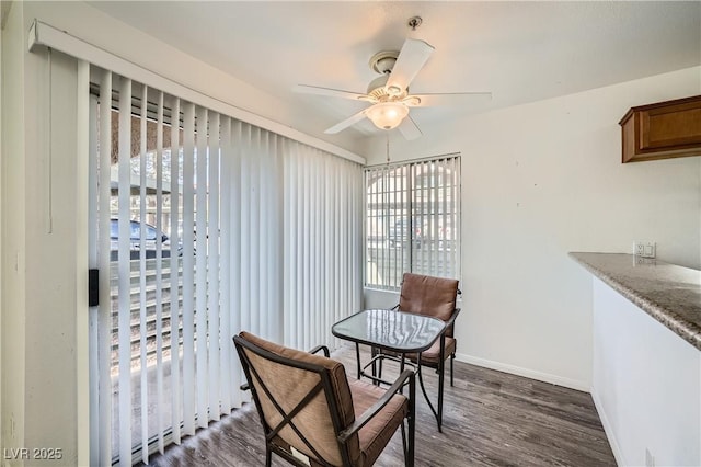 dining space featuring dark wood-style floors, ceiling fan, and baseboards