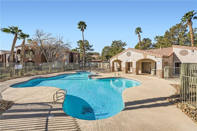 community pool with a patio area and fence