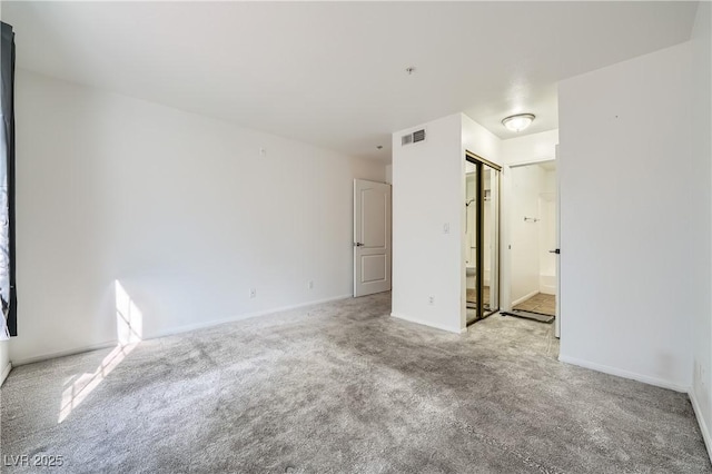 spare room with carpet floors, visible vents, and baseboards