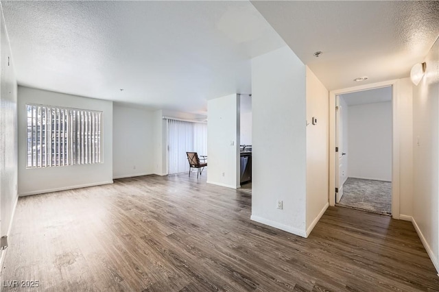 interior space with a textured ceiling, wood finished floors, and baseboards