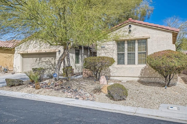 view of front facade with stucco siding, concrete driveway, an attached garage, and a tiled roof