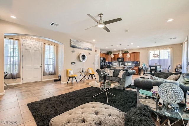 living room featuring light tile patterned floors, visible vents, arched walkways, and recessed lighting