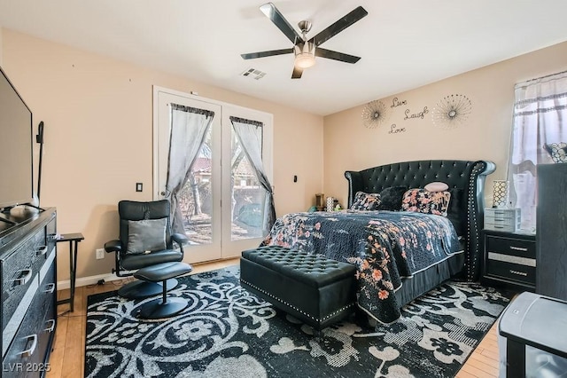 bedroom with wood finished floors, visible vents, baseboards, ceiling fan, and access to outside