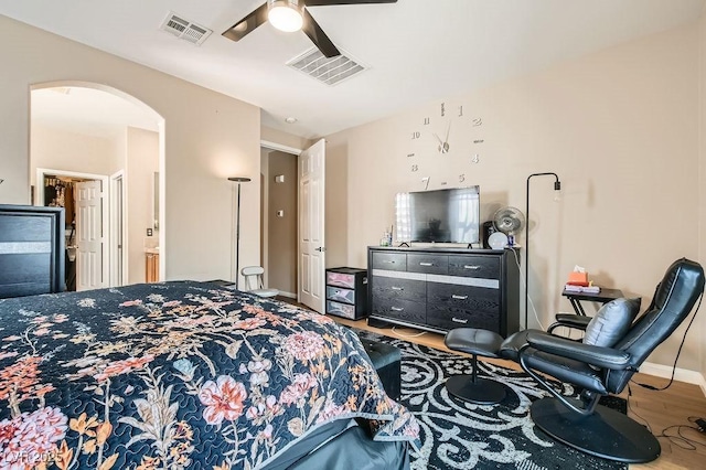 bedroom featuring arched walkways, visible vents, a ceiling fan, and wood finished floors