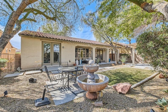 back of house featuring fence, stucco siding, french doors, a tile roof, and a patio area