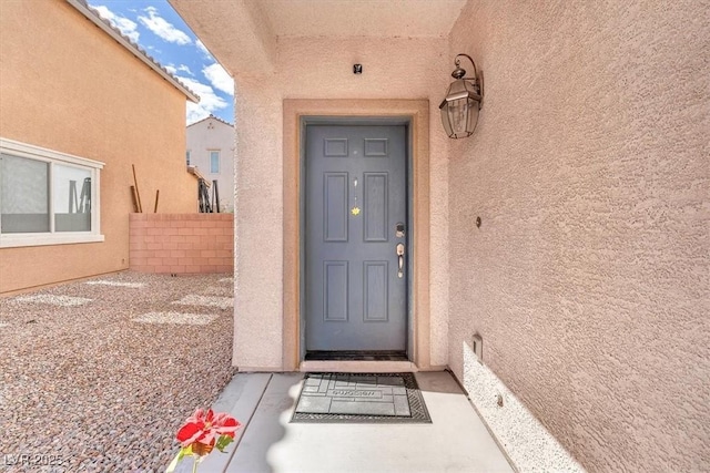 property entrance featuring fence and stucco siding