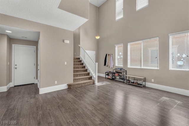 interior space featuring stairway, wood finished floors, a towering ceiling, and baseboards