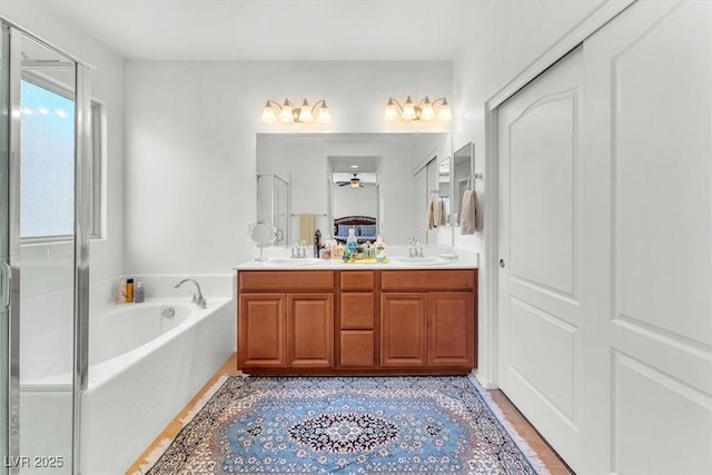 full bathroom featuring double vanity, a stall shower, a sink, and a bath