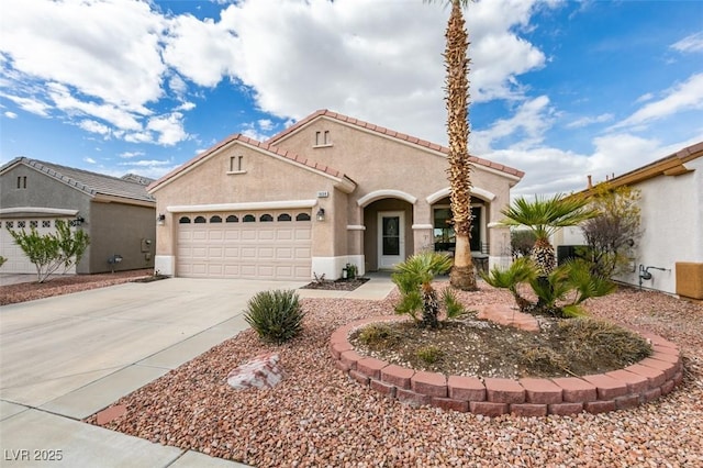 mediterranean / spanish home featuring concrete driveway, a tile roof, an attached garage, and stucco siding