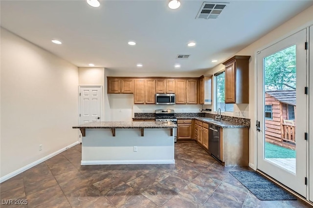 kitchen featuring stainless steel appliances, visible vents, a kitchen island, and dark stone countertops