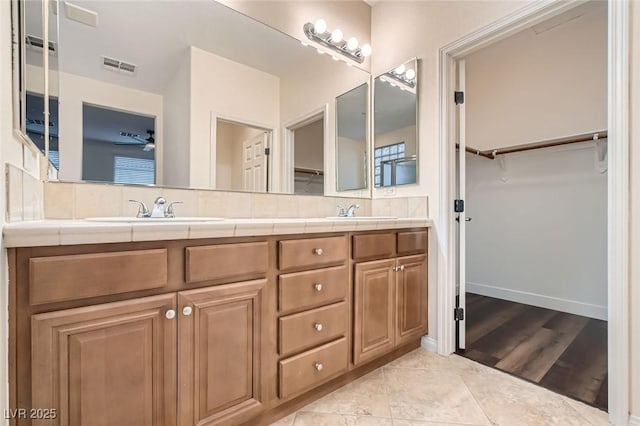 bathroom with double vanity, tasteful backsplash, visible vents, and a sink