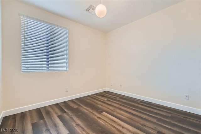 spare room with visible vents, baseboards, and dark wood-type flooring