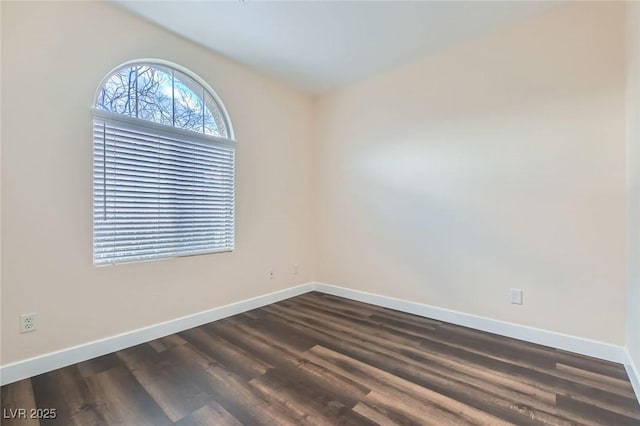 unfurnished room featuring baseboards and dark wood finished floors