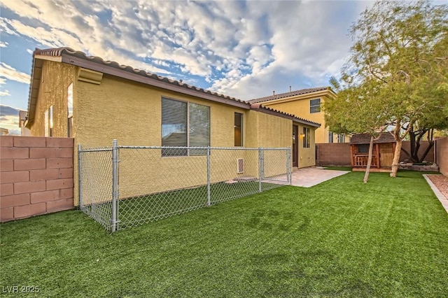 rear view of property with a fenced backyard, a tiled roof, a lawn, and stucco siding