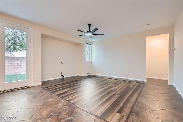 tiled spare room featuring a ceiling fan and baseboards