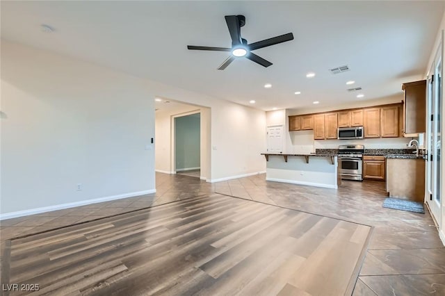 kitchen with dark countertops, appliances with stainless steel finishes, open floor plan, and recessed lighting