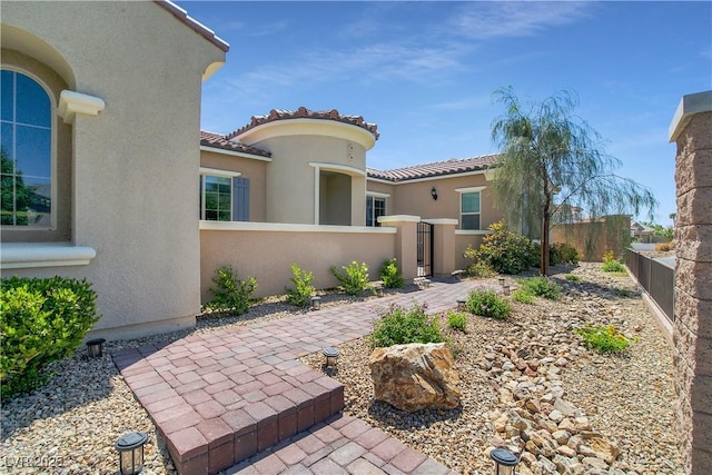 exterior space with a fenced front yard, a gate, a tiled roof, and stucco siding