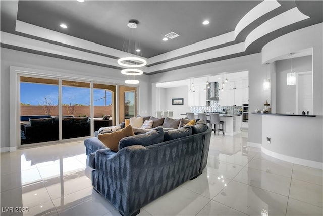 living room with light tile patterned floors, a raised ceiling, visible vents, and baseboards