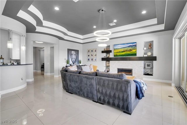 living room featuring recessed lighting, visible vents, baseboards, a lit fireplace, and a tray ceiling