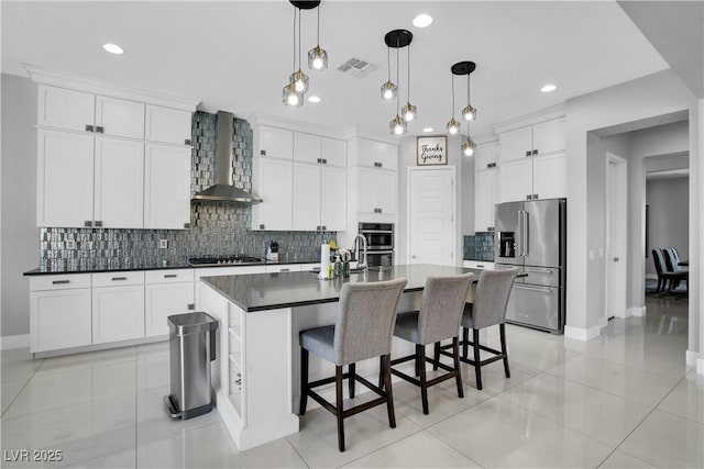 kitchen with visible vents, appliances with stainless steel finishes, decorative backsplash, wall chimney exhaust hood, and dark countertops