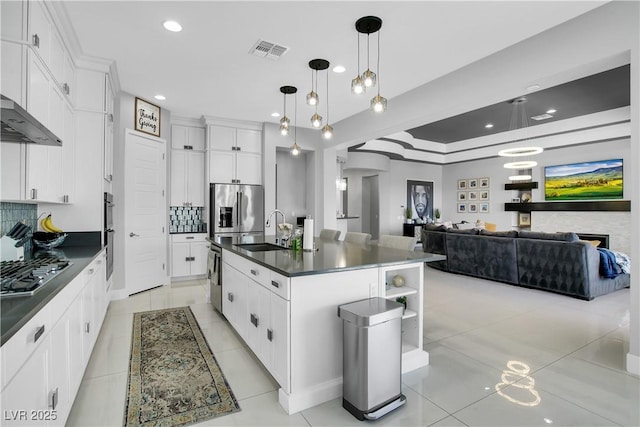 kitchen with stainless steel appliances, a sink, visible vents, tasteful backsplash, and dark countertops