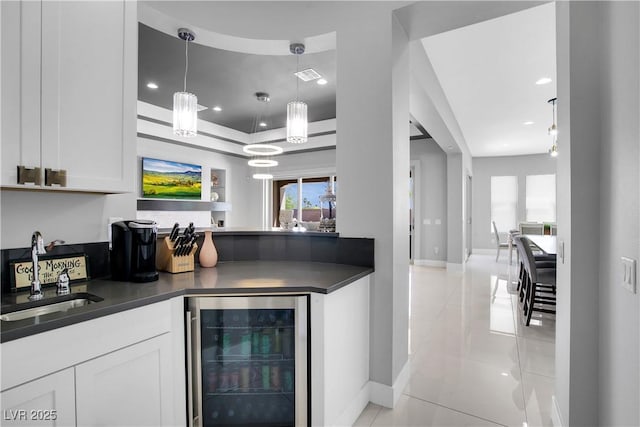 kitchen featuring beverage cooler, dark countertops, a sink, and white cabinets