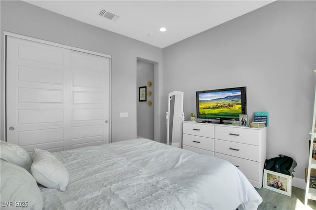 bedroom with recessed lighting, visible vents, a closet, and wood finished floors