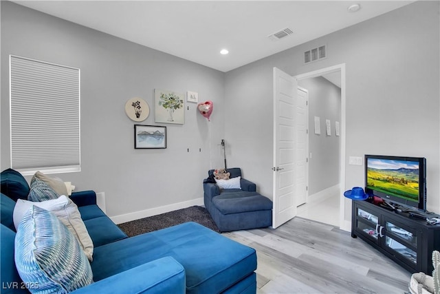 living area featuring light wood finished floors, baseboards, and visible vents