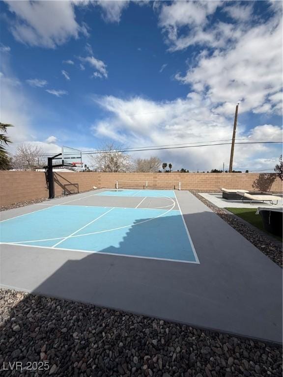 view of basketball court with basketball hoop and a fenced backyard