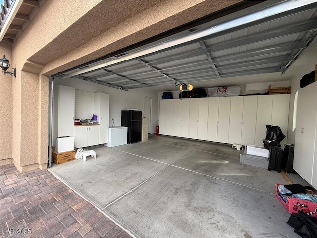 garage with freestanding refrigerator and a garage door opener