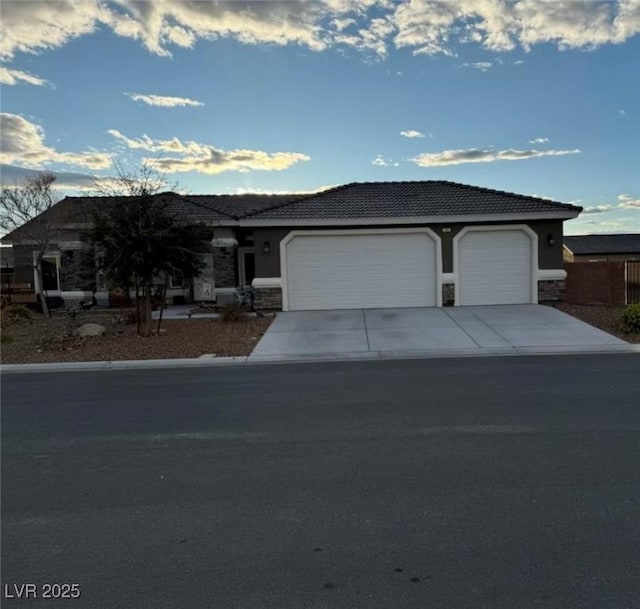 ranch-style house with a garage, stone siding, driveway, and stucco siding