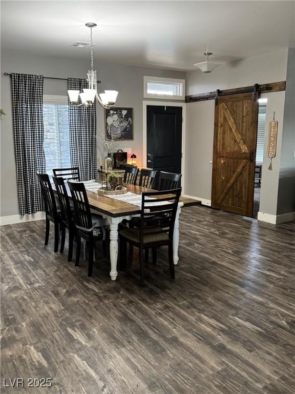 dining room with a barn door, a notable chandelier, wood finished floors, visible vents, and baseboards