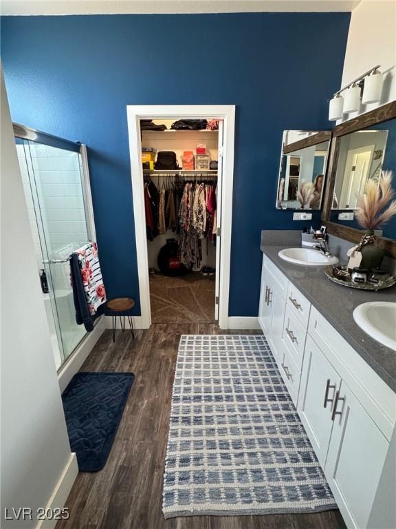 bathroom featuring a stall shower, a sink, a spacious closet, and baseboards