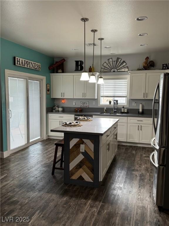 kitchen featuring visible vents, dark wood finished floors, freestanding refrigerator, and white cabinetry