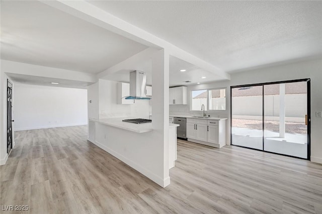 kitchen with island exhaust hood, light countertops, stainless steel dishwasher, white cabinetry, and a sink