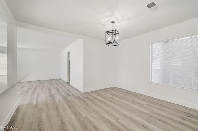 unfurnished dining area featuring light wood-type flooring, visible vents, baseboards, and an inviting chandelier