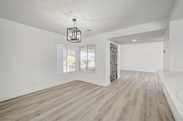 unfurnished dining area featuring a chandelier, visible vents, light wood-style flooring, and baseboards