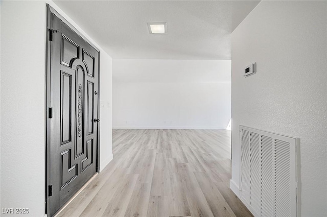 corridor featuring light wood-style floors, baseboards, and visible vents