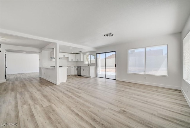 unfurnished living room featuring recessed lighting, visible vents, a sink, light wood-type flooring, and baseboards