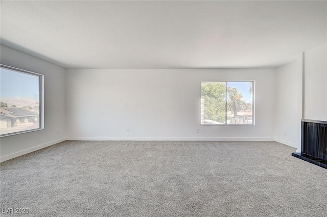 unfurnished living room featuring carpet flooring and baseboards